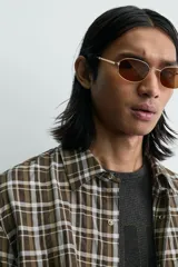 Camisa de corte relajado con estampado de cuadros en tonos marrones y blancos. Presenta cuello clásico, cierre frontal de botones, manga larga con puños abotonados y un bolsillo plastrón en el pecho.