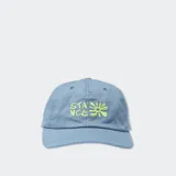 Gorro de tela color azul claro, estilo dad hat, con bordado frontal que dice "STANCE" y un diseño de flor estilizada en color verde lima.