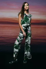 Mono largo con estampado de hojas en tonos verde, blanco y negro, con cinturón negro y zapatillas deportivas verdes.