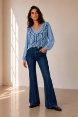 Blusa celeste de manga larga con escote en V y volados en cascada ribeteados en color oscuro. Cuenta con puños elásticos.