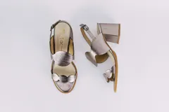 Sandalias doradas de cuero con taco cuadrado y diseño de ondas en el empeine y en la puntera. Cierre con hebilla en el tobillo.