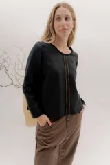 Remera negra de manga larga con escote a la base. La parte delantera es de lino con un bordado central en color tostado, y la espalda es de algodón con spandex.