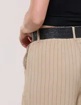 Pantalón wide leg blanco con finas rayas verticales oscuras, tiro alto, bolsillos laterales y pinzas frontales. Incluye un cinturón trenzado de rafia con hebilla rectangular.