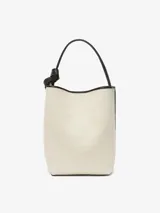 Bolso de hombro tipo bucket color crema, con detalles en cuero negro y herrajes dorados.