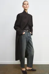 Jeans de tiro alto con corte barrel y diseño tapered, confeccionados en denim con efecto lavado y detalle de raya planchada. Presentan cintura con trabillas, cierre frontal con cremallera y botón, y bolsillos funcionales en delantero y espalda.