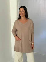Sweater de punto color visón con cuello en V, mangas largas con puños acanalados y bolsillos frontales tipo parche.