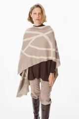 Ruana de tejido de punto con diseño geométrico de líneas curvas en tonos beige y visón. Presenta una caída fluida y envolvente, ideal para usar como capa sobre otras prendas.