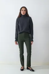 Pantalón de tiro medio y fit slim, color verde militar. Confeccionado en tejido elasticado, no presenta bolsillos visibles y cuenta con cierre frontal oculto.
