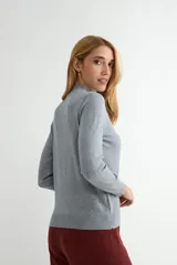 Polera de punto color beige, con cuello alto y mangas largas, de diseño básico y ajuste clásico.