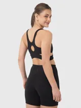 Top deportivo negro de escote redondo, con bandas elásticas cruzadas bajo el busto y abertura en la espalda.