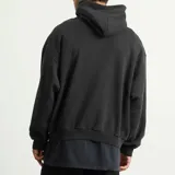 Hoodie Balenciaga de corte oversize en color negro, con capucha y bolsillo frontal tipo canguro. Presenta el logo de la marca y el emblema BB estampados en el pecho en tono gris oscuro.
