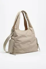 Bolso bandolera de gran tamaño con estructura blanda, confeccionado en nylon color beige. Cuenta con doble asa de mano, asa regulable de tejido, cierre principal con cremallera y bolsillos laterales con cierre. Incluye logo metálico de la marca en el frente.