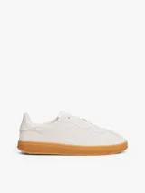Zapatillas de corte bajo Tommy Hilfiger de inspiración retro, confeccionadas en ante color blanco con suela de goma color caramelo. Presentan monograma TH tonal en el lateral, detalles de ventilación en la puntera y cierre con cordones.