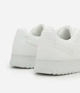 Championes urbanos blancos de cuero sintético con efecto floater, puntera redonda y perforaciones.