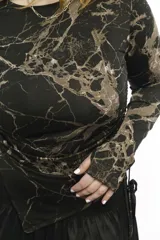 Top de manga larga color negro, confeccionado en jersey elástico. Presenta un diseño asimétrico con jaretas laterales regulables que permiten ajustar el largo y el volumen, y aberturas para los pulgares en los puños.