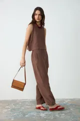 Cartera de hombro pequeña de cuero color tostado con detalles de bordado artesanal y costuras en tono chocolate en los bordes y la solapa. Cuenta con correa larga ajustable.