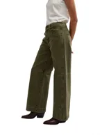 Pantalón de jean verde militar, corte ancho y relajado, con detalles de costuras reforzadas en rodillas y botones decorativos en los tobillos.