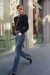 Jeans de tiro bajo y cintura ancha, con diseño bootcut de corte evasé desde la rodilla. Cuenta con cinco bolsillos y cierre frontal con cremallera y dos botones metálicos. Color azul con efecto desgastado.