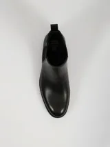 Botin tipo Chelsea de cuero sintético negro, con paneles laterales elásticos, tirador trasero y suela de goma dentada.