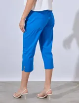 Pantalón capri de gabardina elastizada color celeste, con bolsillos simulados delanteros y bolsillos aplicados traseros. Tiene pretina ancha, corte recto y detalle calado en el ruedo.