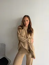 Buzo de punto color marrón chocolate, con cuello redondo y diseño holgado de manga larga con textura de trenzas verticales.