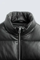 Cazadora acolchada de corte relajado confeccionada en tejido efecto piel. Presenta cuello subido, cierre frontal con cremallera, manga larga con puño elástico interior y bolsillos laterales de vivo.