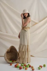 Vestido largo de gasa estampada con flores en tonos de verde y amarillo sobre fondo blanco. Tiene cintura elastizada y terminación en volados.