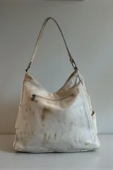 Cartera tipo hobo de cuero natural con efecto desgastado, diseño envolvente, manija de hombro y detalle de la marca escrito en el frente.