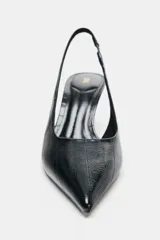 Zapato destalonado de tacón medio fino, con acabado en punta y textura con efecto relieve en el cuerpo. Cuenta con tira trasera elástica ajustable.