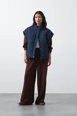 Pantalón de corte holgado y pierna ancha, con cintura elástica ajustable mediante cordón. Presenta bolsillos laterales y costuras verticales decorativas que recorren el frente de las piernas.