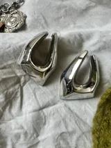 Par de caravanas plateadas con forma irregular.