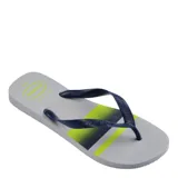 Ojotas Havaianas de diseño clásico con base gris y estampado geométrico en tonos azul y verde neón. Presentan tiras de goma en color azul marino con textura grabada y logo de la marca en relieve.