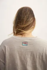 Remera color crema de corte holgado, con mangas cortas y costuras a la vista en color ocre.