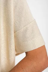 Remera color crema con brillo, de corte amplio y mangas cortas.