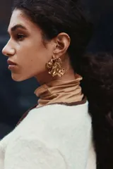 Saco corto de tejido sherpa color crema, con cuello redondo y cierre frontal de botones marrones. Presenta ribetes de tela marrón en el escote y la tapeta frontal.