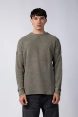 Buzo de corte oversize confeccionado en tela waffle de algodón con proceso de teñido acid wash. Presenta cuello redondo con detalle de costura en X y mangas largas con puños acanalados.