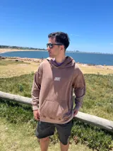 Hoodie de algodón con efecto lavado a la piedra (acid wash) en tono gris oscuro/negro. Presenta un corte relajado (oversize), capucha amplia, bolsillo canguro frontal y el logo "DROPZ" estampado en blanco en el pecho.