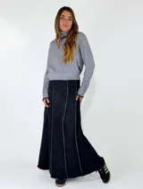 Pollera larga de denim color negro, con diseño de paneles verticales y bordes deshilachados.