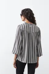 Camisa de manga larga color marrón con estampado de lunares blancos, cuello mao y cierre frontal con botones.