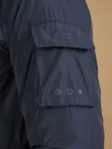 Campera de abrigo azul marino con capucha, cierre frontal con botones y cremallera, múltiples bolsillos y forro interior naranja.