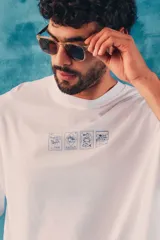 Remera oversize blanca de manga corta, con cuello redondo y estampa frontal de ilustraciones en tono azul con temática costera.