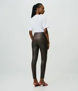 Pantalón skinny de mujer Cortelle, confeccionado en sarga de acabado resinado color marrón oscuro, con cintura mediana, bolsillos y cierre delantero tradicional.