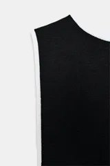 Body negro de manga sisa con escote barco y ribetes de contraste blancos en el cuello y los bordes de la pierna. Cierre inferior con botones a presión.