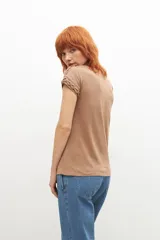 Remera negra de corte recto, con cuello en V y detalle de trenzas en los hombros.