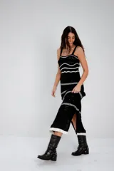 Vestido largo de tejido de punto negro, con tirantes finos y diseño calado con franjas horizontales blancas en el busto y patrones en el ruedo.