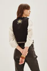 Chaleco negro con bordados dorados y lentejuelas, diseño con estrellas y motivos geométricos, cierre frontal y forro interior.