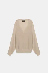 Jersey de punto metalizado color beige, con escote en V y manga larga.