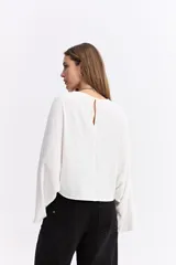Blusa de corte relajado y fit holgado, con mangas largas amplias y textura sutil. Presenta un diseño minimalista con caída suave.