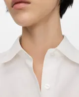 Camisa de algodón color blanco, con cuello camisero, manga larga con puño abotonado, cierre frontal con botones y un bolsillo aplicado en el pecho.