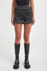 Short negro de tejido de punto con lurex y detalle de flecos en el ruedo.